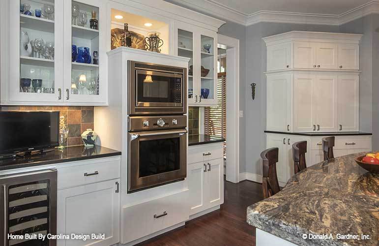厨房有白色和玻璃前柜，不锈钢电器，花岗岩台面，和早餐吧。