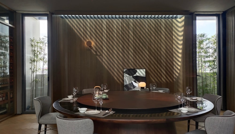 这是一个大圆形的深色木制餐桌，与墙壁的浅色木质色调形成鲜明对比。