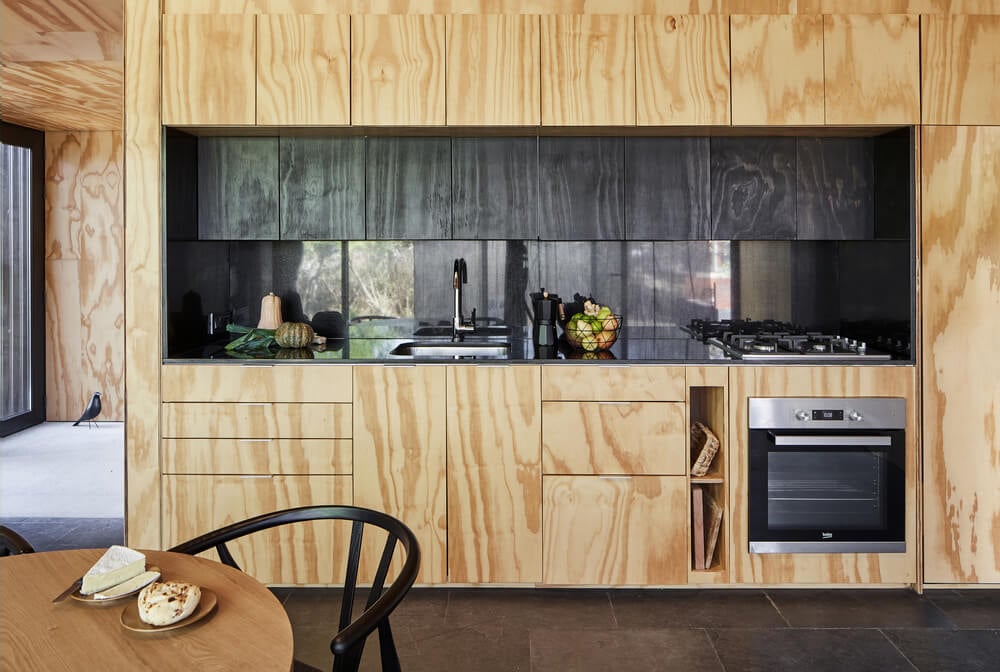 这是一个近距离观察现代橱柜的小厨房，与深色台面、后挡板和电器形成对比。