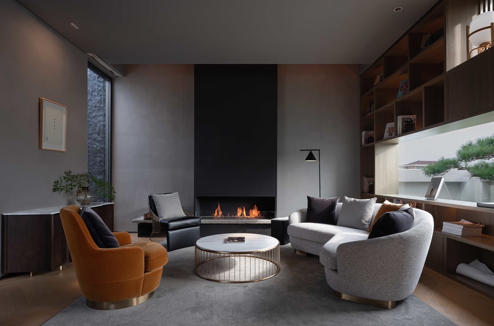 客厅的另一侧有一座现代化的壁炉，可以温暖围绕白色圆形咖啡桌的沙发。