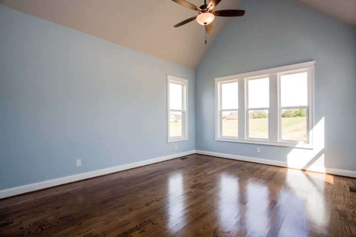 主卧室与淡蓝色的墙壁,抛光硬木地板,white-framed windows,大教堂天花板。