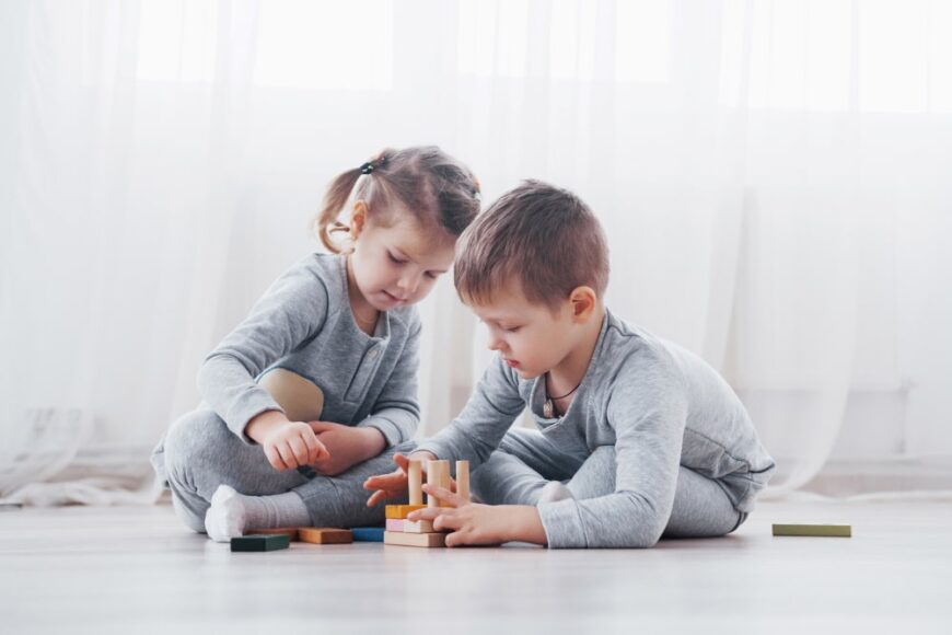 两个孩子在地板上玩积木和玩具。