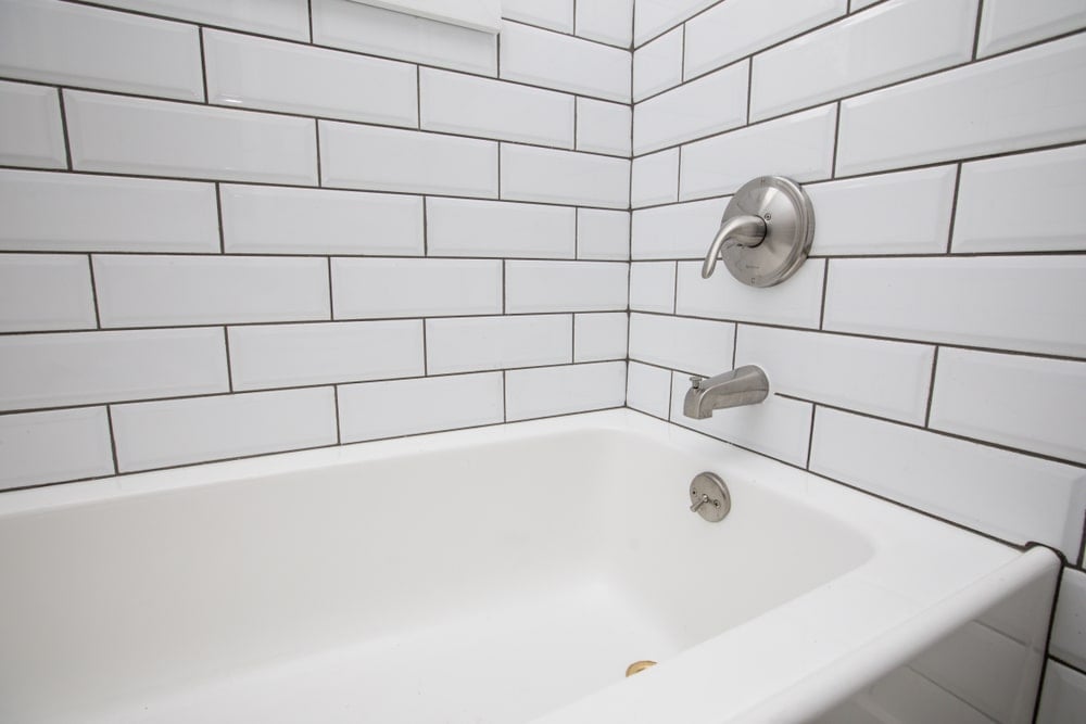 浴缸的特写与铬固定装置安装在瓷砖墙上。