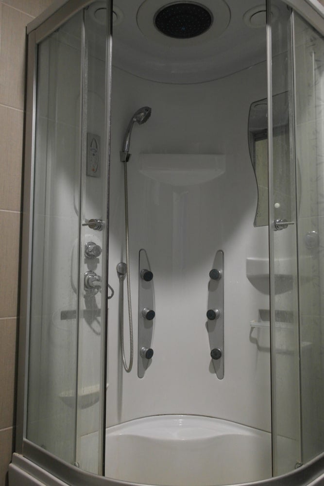 豪华水疗按摩淋浴室，设有头顶淋浴，淋浴手柄，恒温控制和镜子。