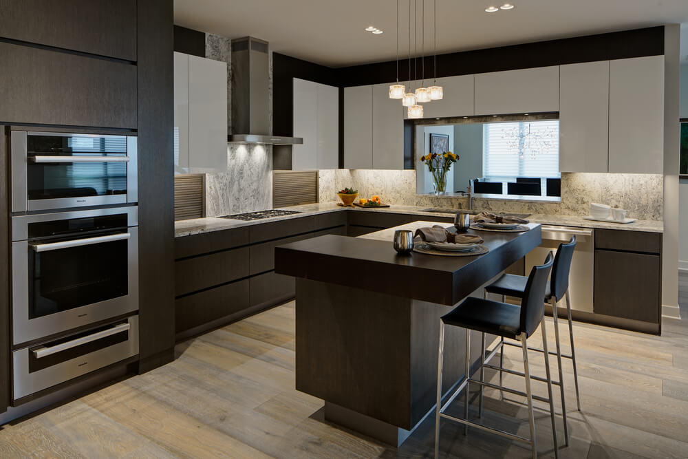 光滑的厨房，现代化的白色悬垂橱柜，不锈钢电器，以及宽木板地板上的凸起岛。