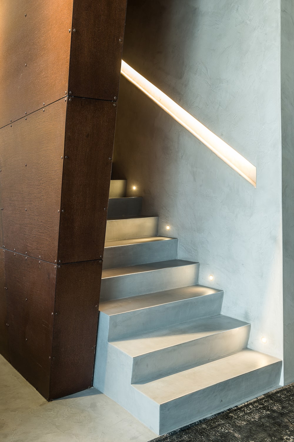 这是一个近距离观察楼梯，它的一侧有木镶板墙，另一侧有现代照明。
