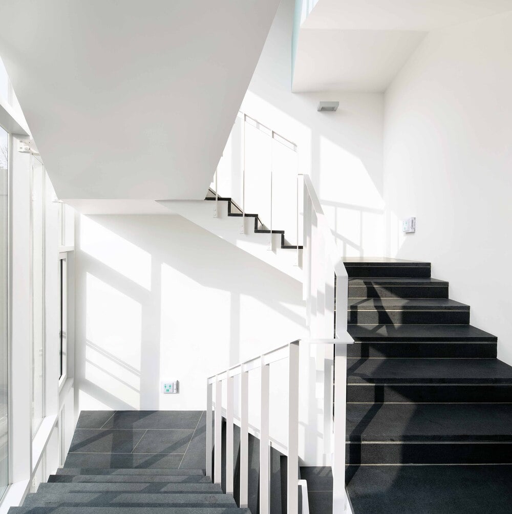 这是对楼梯的近距离观察，深色的台阶与白色的墙壁和天花板形成对比。