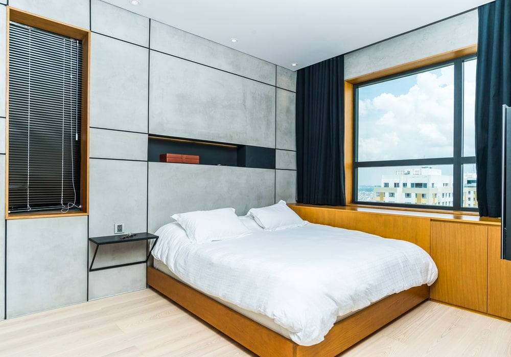 主卧室里有一张大台床，床与嵌在墙上的木制橱柜相连，窗户下有深色窗帘。