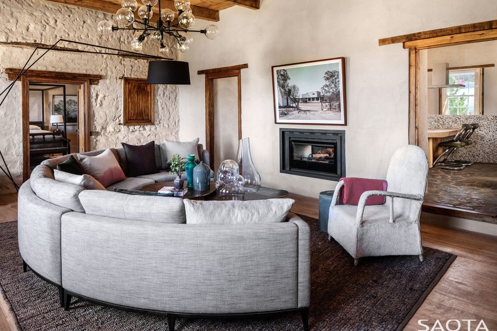 这是一间客厅，客厅里有一张大弧形组合沙发，对面是一座现代风格的壁炉，壁炉顶上有一幅墙上的艺术品。