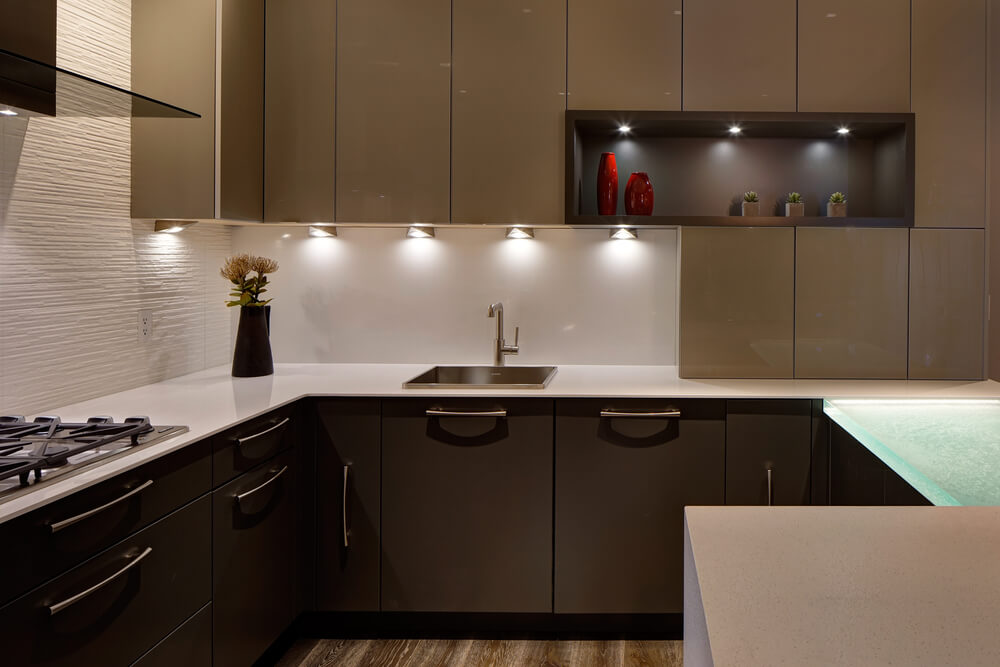 这个现代化的厨房包括高光泽的橱柜，白色的柜台，和一个宏伟的玻璃顶部吃吧。