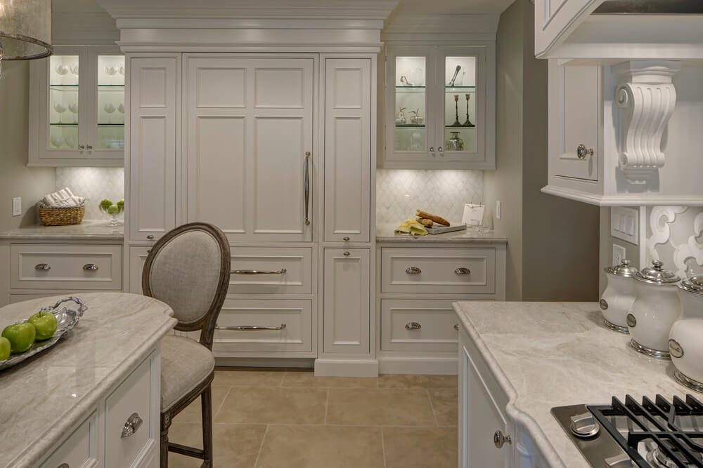 厨房包括白色橱柜、玻璃前悬垂橱柜和内置灶台。