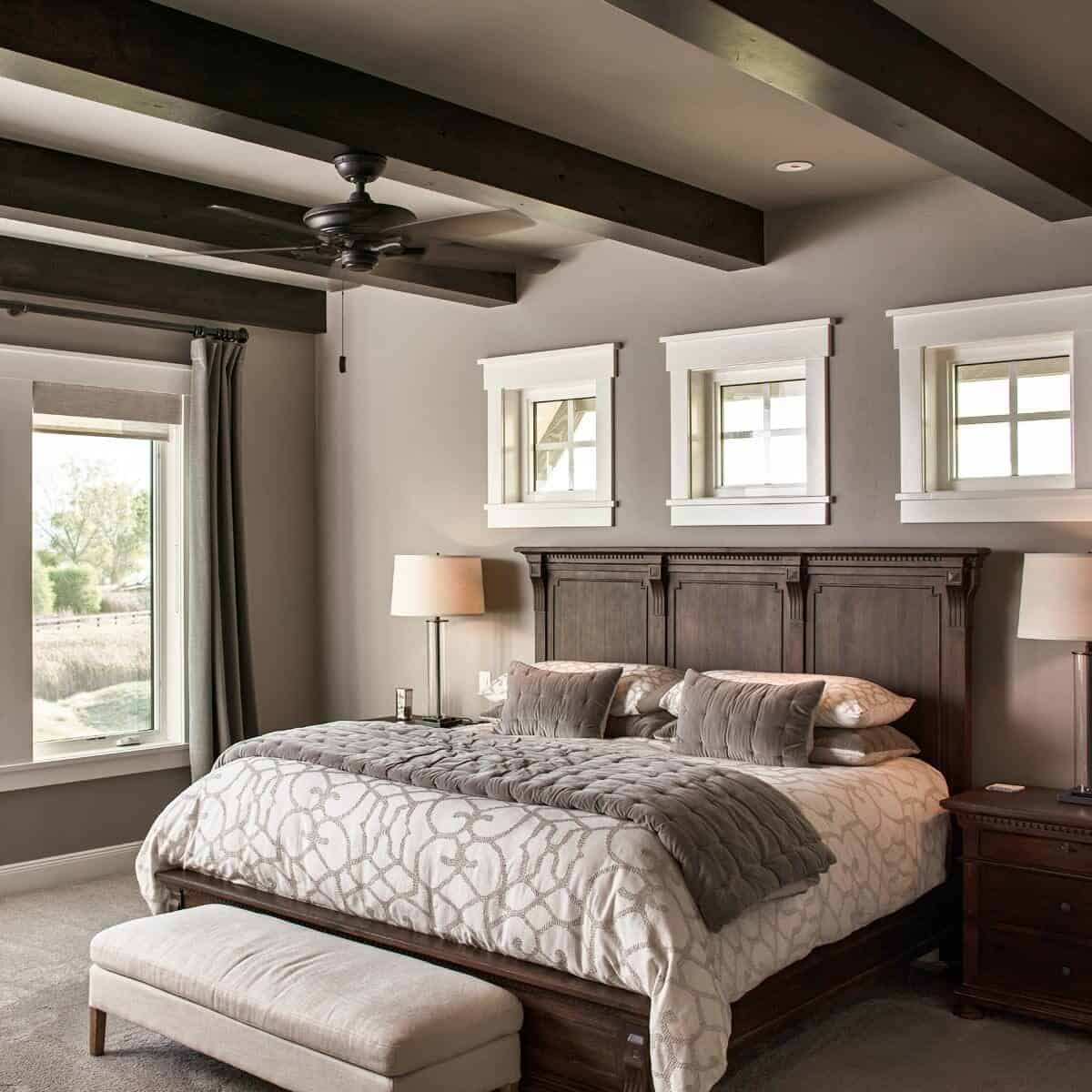 主卧室有横梁天花板，地毯地板，和一张舒适的木床，上面有三扇小窗户。