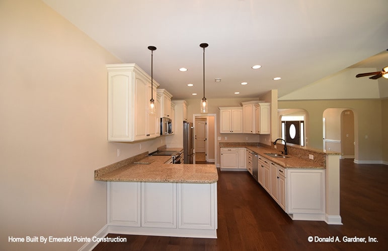 厨房里有白色的橱柜、花岗岩台面和一座两层的半岛式建筑。