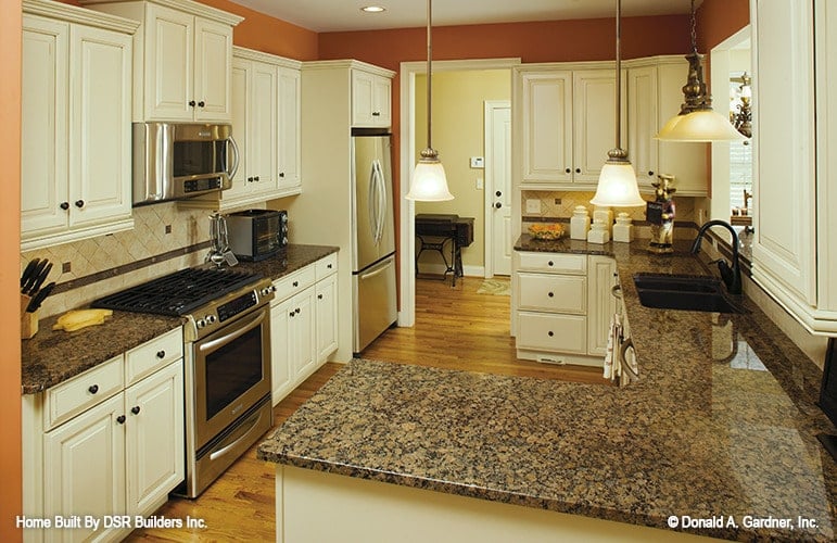 厨房配有花岗岩台面、不锈钢电器、白色橱柜和双碗水槽。