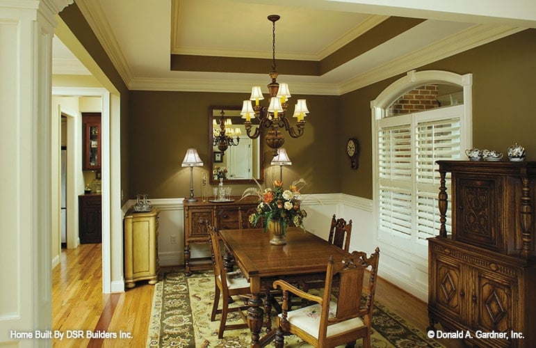 正式的餐厅有木制家具，花卉区域地毯，托盘天花板，棕色墙壁装饰着白色护壁板。