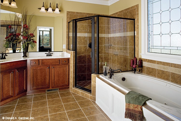 主浴室有两个水槽，一个角落的淋浴，和一个放置在彩色玻璃窗下的浴缸。