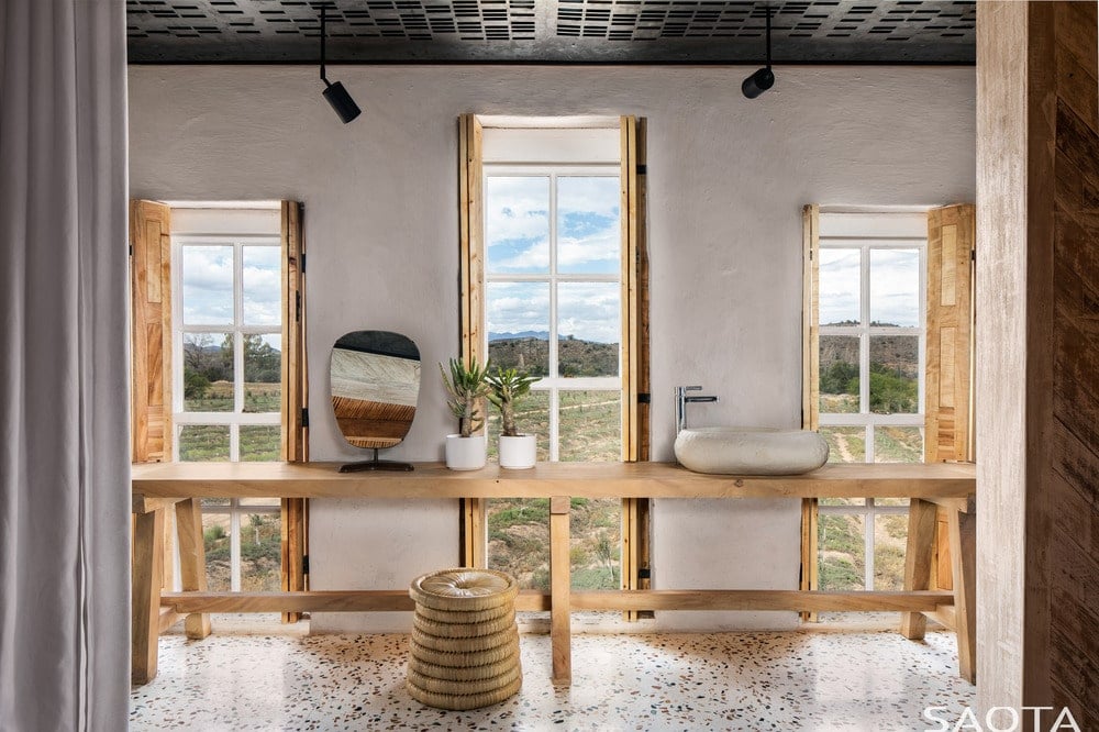 宽敞的浴室有一种乡村的感觉，它的长木桌作为水池的支撑，与高窗户搭配。