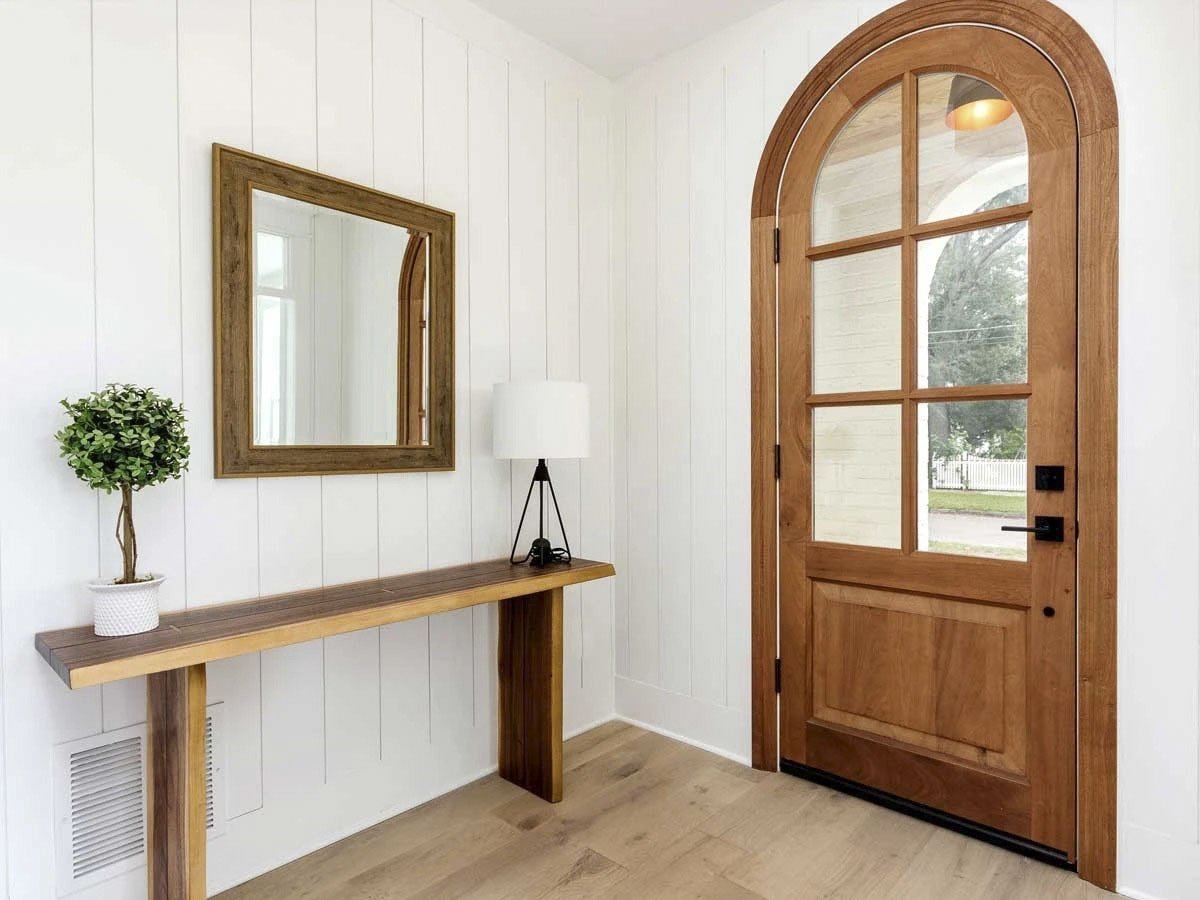 门厅里有一张木制的控制台桌子，一面配套的镜子固定在床头板墙上。