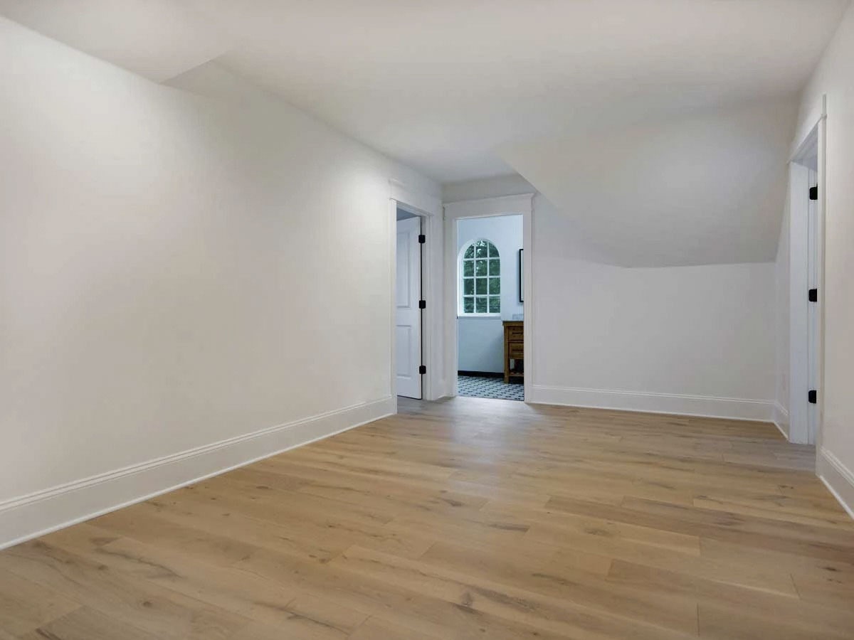 另一间卧室铺着宽大的木板地板，赤裸裸的白墙镶着底座。