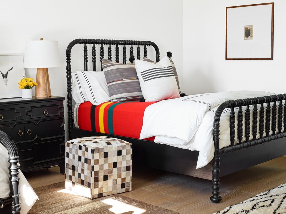 这间卧室以深色木床和深色木制床头抽屉为主，与白色墙壁形成对比。