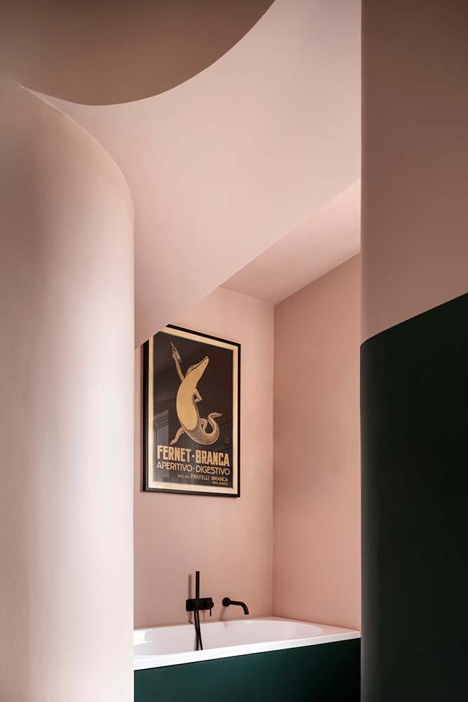 这是浴室的粉红色墙壁和浴缸上方的壁挂式艺术品。
