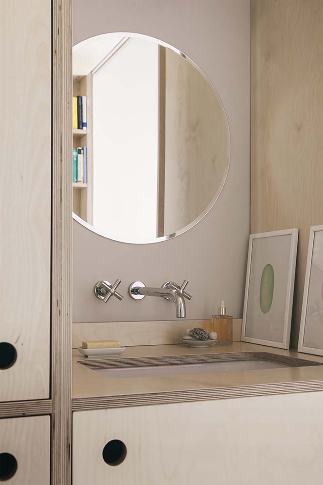 这是一个近距离观察浴室的水槽安置在一个大的木制结构，顶部有一个圆形的镜子。
