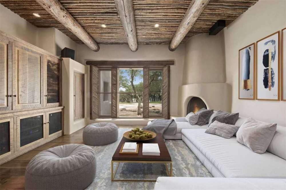 家庭娱乐室里有一张u型浅灰色组合沙发，靠墙而立，对面是一个大型木结构，与裸露的横梁的木质天花板相匹配。图片来自Toptenrealestatedeals.com。
