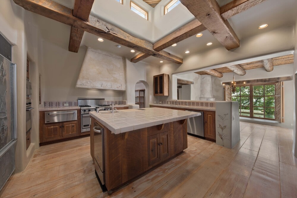 这是厨房的另一个视图，展示了围绕厨房岛上天窗的天花板上厚厚的裸露的木梁。图片来自Toptenrealestatedeals.com。