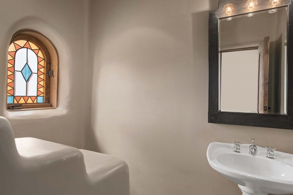 化妆室有土坯墙和一个漂浮的白瓷水槽，上面有一面壁挂式镜子。图片来自Toptenrealestatedeals.com。