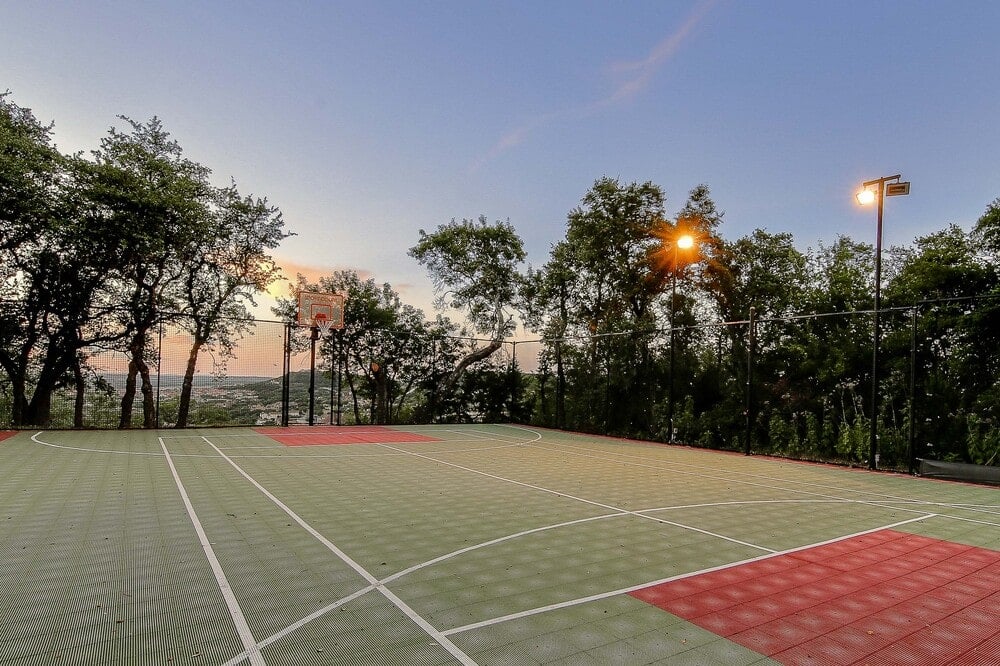 这处房产还有一个网球场，有着专业的外观，周围环绕着高大的树木和灯柱。图片来自Toptenrealestatedeals.com。