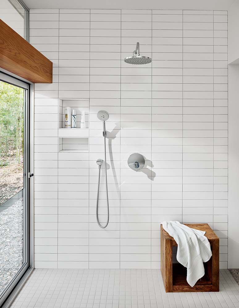 浴缸区对面是开放式淋浴区，同样铺着白色地铁瓷砖。