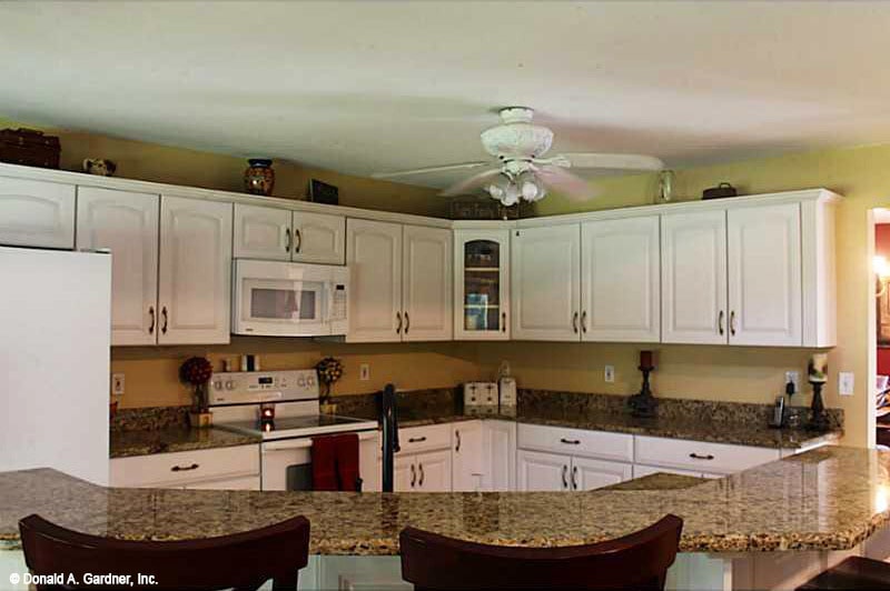 厨房提供白色电器，定制橱柜，花岗岩台面，和一个凸起的吃吧。