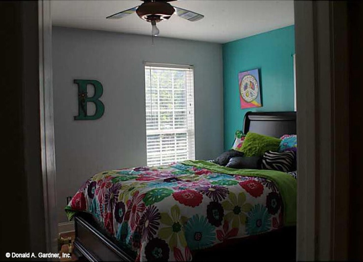 这间卧室有一面蓝绿色的墙壁和一张深色的木床，床上铺着花毯。