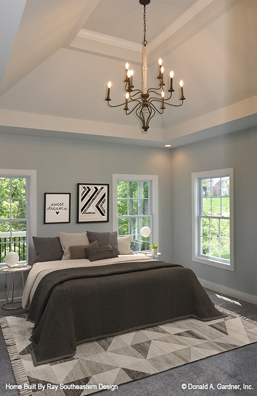 主卧室有灰色的墙壁，高高的拱形天花板上安装着一盏华丽的枝形吊灯。