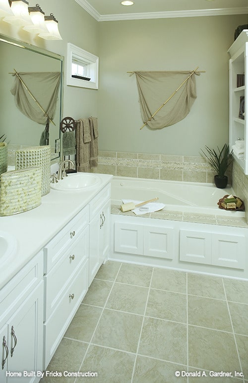 主浴室设有双洗手池梳妆台和一个深泡浴缸，装饰着米色挂毯。