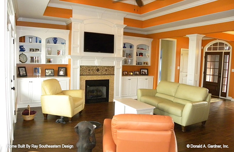 客厅有明亮的橙色墙壁，多色座椅，壁炉，和一个惊人的台阶天花板。