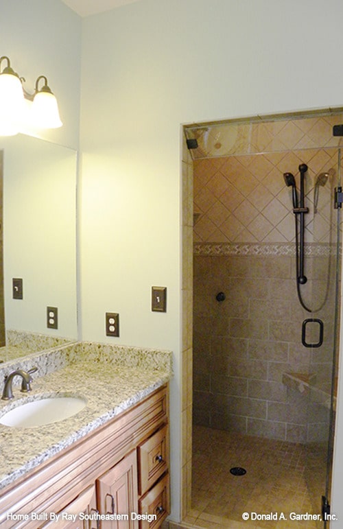 主浴室带木制梳妆台和一间步入式淋浴间，角落里有瓷砖长凳和锻铁设备。