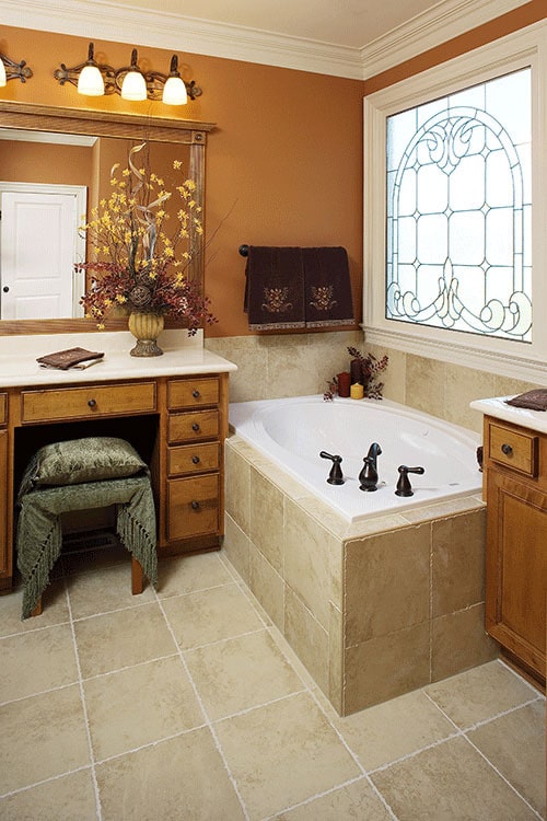 主浴室里有木制梳妆台，彩色玻璃窗下有一个深浴缸。