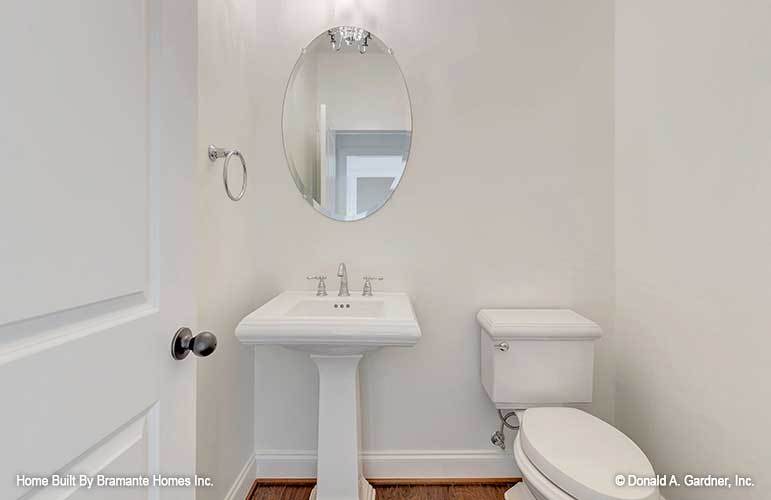 盥洗室有一个传统的厕所和一个顶部有椭圆形镜子的洗手台。