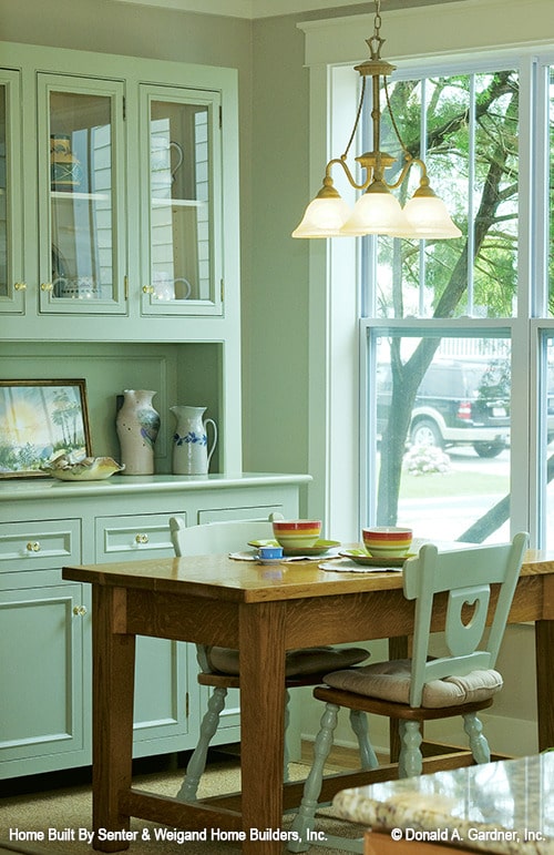 早餐角落里有一个白色的展示柜和一张木制餐桌，配有软垫椅。