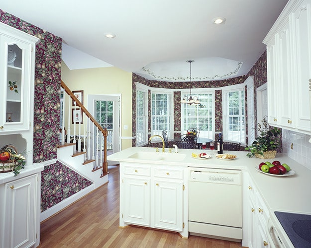 厨房里有白色橱柜和毗邻的早餐角，顶部有装饰性的托盘天花板。
