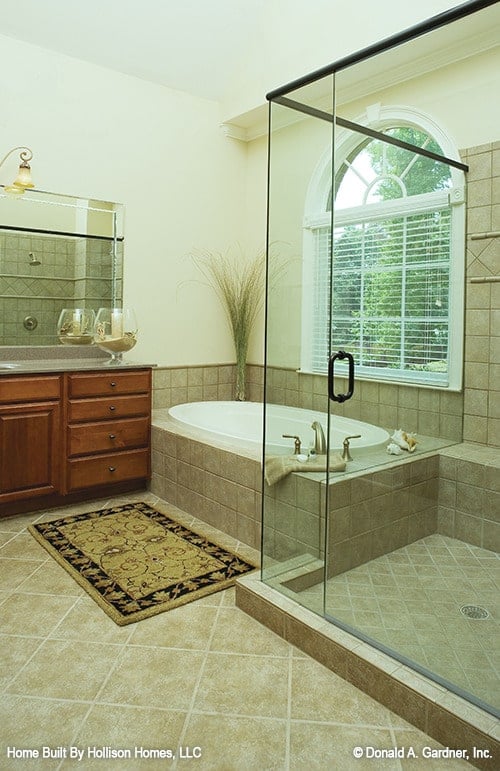 主浴室有一个木制梳妆台，一个步入式淋浴间，和一个带有花卉镶边地毯的浴缸。
