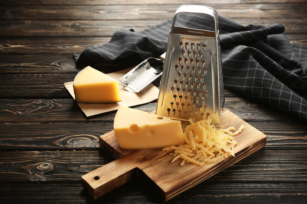 在案板上放一块奶酪的刨丝器。