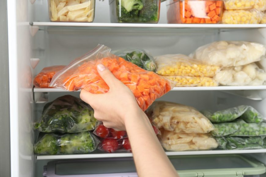 一个女人在冰箱中安排各种食物的可重复密封的袋子。