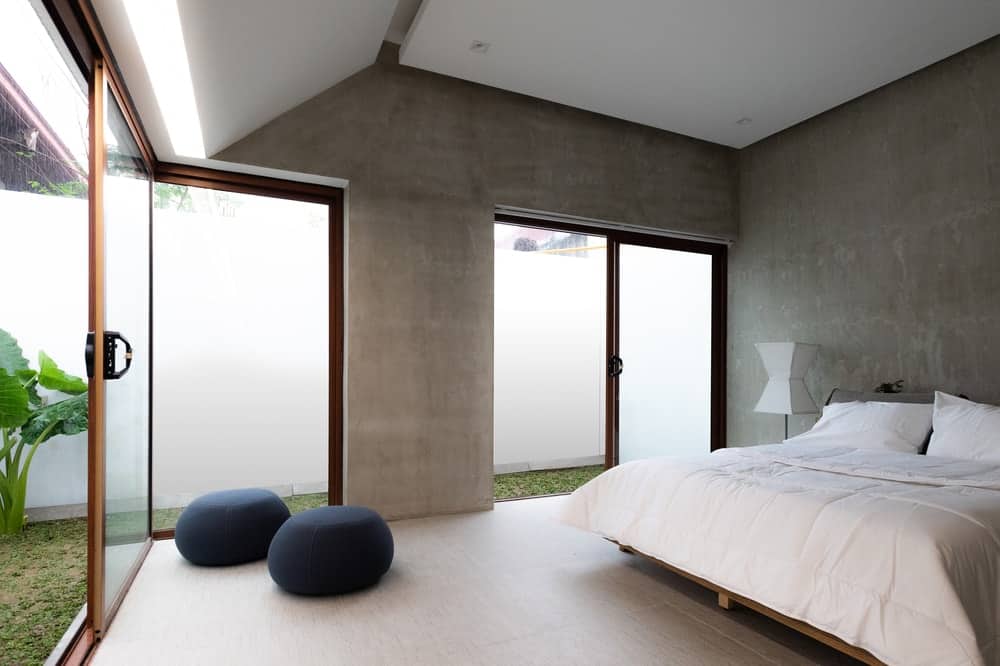 这是主卧室的外观，墙壁和天花板上有灰色和白色的色调，与被玻璃门照亮的白色床相匹配。