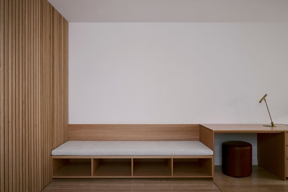 这是对客厅的近距离观察，客厅有一个内置的木沙发，下面有架子，并连接到一侧的木板条面板上。