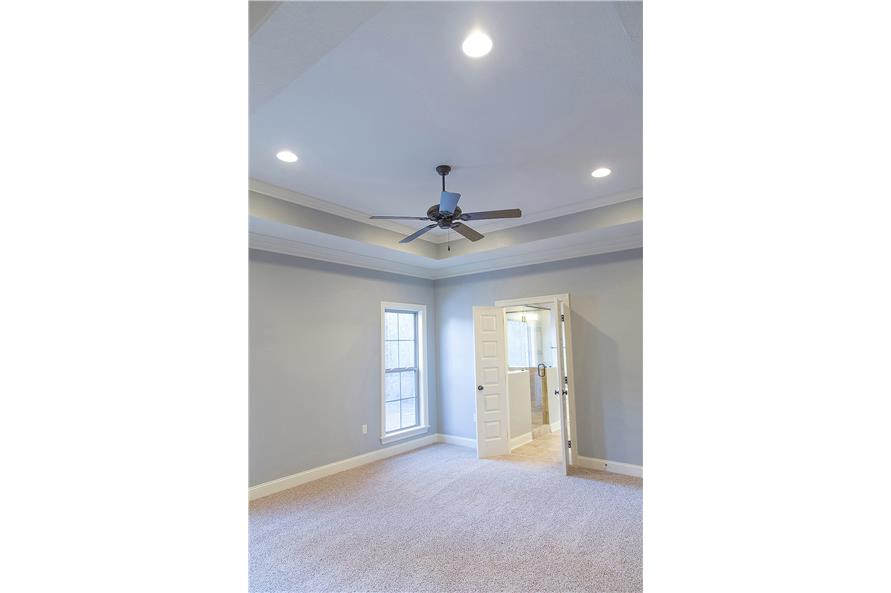 主卧室有地毯地板和托盘天花板，安装了风扇和嵌入式灯。
