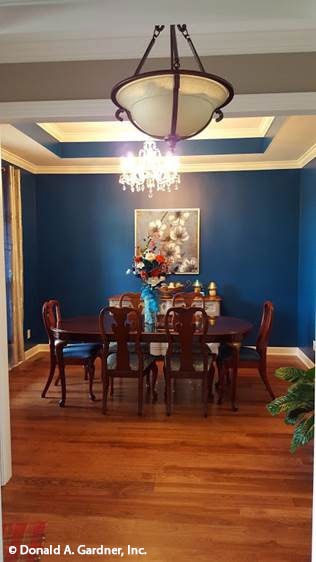 正式的餐厅有蓝色的墙壁，木制的家具，和一个令人惊叹的托盘天花板装饰着一个串珠吊灯。