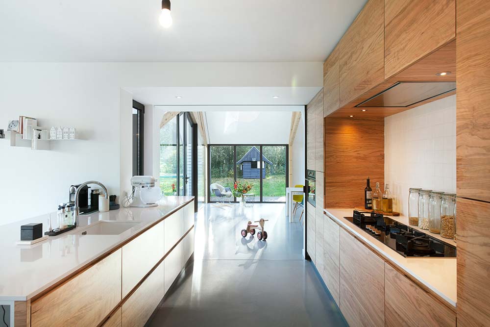 这是一个狭长的厨房，棕色的木制橱柜和抽屉搭配明亮的柜台。