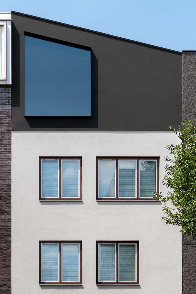 这是一个近距离观察房子前面的上层，其白色和深灰色的现代设计façade。